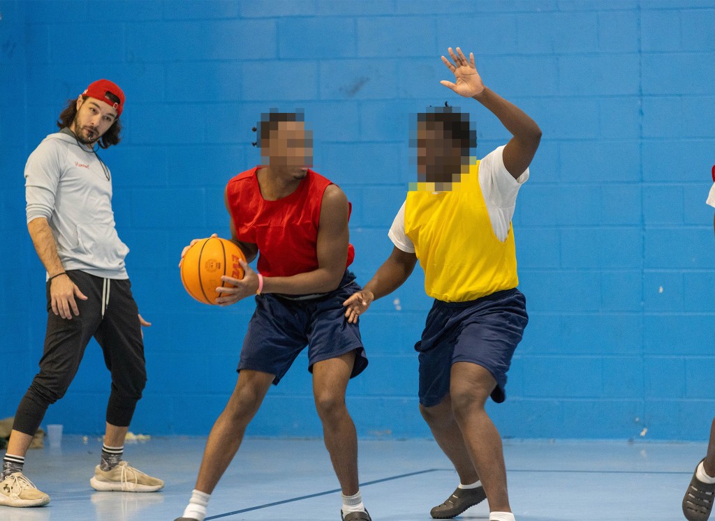Volunteers and youth playing basketball together during a sport-based program session